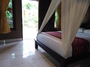 a bedroom with a bed with a mosquito net at Suka Sari Cottages in Pemuteran
