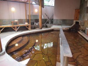 a pool of water with a bench in a room at Tsurusaki Hotel in Oita