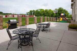 un patio con mesas y sillas, parrilla y parque infantil en GrandStay Residential Suites Hotel Faribault, en Faribault