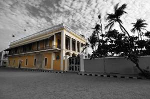 un edificio amarillo con palmeras delante en Villa Gomez en Pondicherry