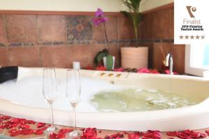 two wine glasses and a bath tub in a bathroom at Lakeside Cottage Luxury B&B in Mount Dandenong