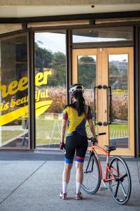 a woman with a helmet standing next to a bike at Wheeler Bed &Bike in Bangsaen