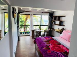 a bedroom with a bed and a balcony with a table at Sherwood Cottage in Nuwara Eliya