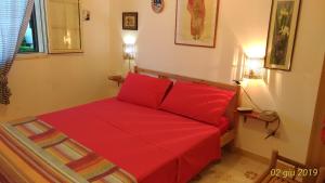 a red bed with two red pillows in a room at Villetta Carati in Torre dell'Orso