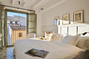 una camera da letto con un letto bianco e un libro sopra di Hotel Basilica a Palma de Mallorca