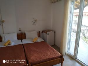 a bedroom with two beds and a large window at Pension Nikolas in Skiathos