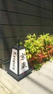 une horloge noire et blanche assise à côté de certaines plantes dans l'établissement Kyogura Bettei Nijo, à Kyoto