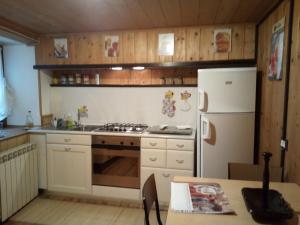 a kitchen with a stove and a white refrigerator at Casa Vacanza PIZZO CAMINO in Calasca Castiglione