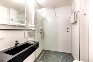 a white bathroom with a sink and a shower at ACHAT Hotel Bad Dürkheim in Bad Dürkheim