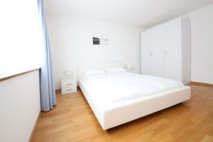 a white bedroom with a white bed and a wooden floor at CITY STAY - Kirchweg in Zurich