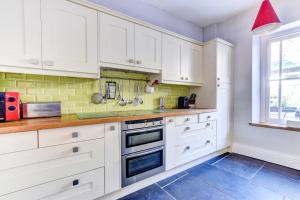una cocina con armarios blancos y una ventana en Bwthyn y Bardd, en Llanstephan