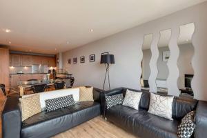 a living room with two leather couches and a kitchen at Modern Riverfront Apt. 10 mins from Hydro/SECC in Glasgow