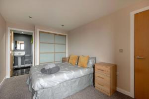 a bedroom with a bed and a dresser in it at Modern Riverfront Apt. 10 mins from Hydro/SECC in Glasgow