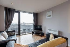 a living room with a couch and a television at Modern Riverfront Apt. 10 mins from Hydro/SECC in Glasgow