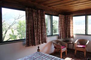 a bedroom with a bed and two chairs and windows at Quinta de S.Vicente in Geraz do Minho