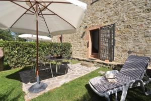 un patio con sombrilla, mesa y sillas en Castellare in Chianti en Gaiole in Chianti