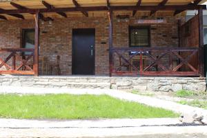 een bakstenen gebouw met een zwarte deur en een veranda bij Сердце Каньона in Kamjanets-Podilsky