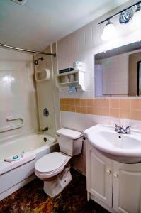 La salle de bains est pourvue de toilettes, d'un lavabo et d'une baignoire. dans l'établissement Wescana Inn, à Le Pas