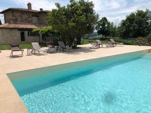 a pool with chairs and a house in the background at Agriturismo Fattoria di Monticello in San Venanzo