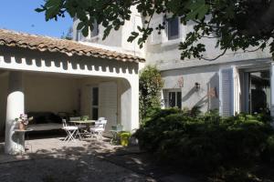 Un patio de una casa con una mesa y sillas. en Le Mas des Figuiers, en Arles