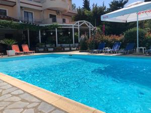 ein großer blauer Pool mit Stühlen und einem Sonnenschirm in der Unterkunft JB Hotel in Sarandë