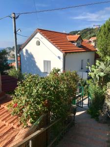 a white house with a red roof and some bushes at Casa del sasso in Bergeggi