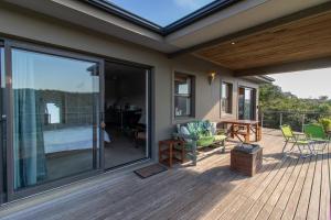 a deck with a glass door and a table and chairs at Nature's Cottage in Kenton on Sea +2 photos