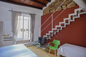 a bedroom with a staircase with a bed and a green chair at Rooms 19 B&B in Palermo