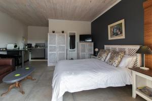 1 dormitorio con 1 cama blanca y sala de estar en Nature's Cottage, en Kenton on Sea