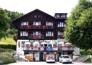 een groot gebouw met auto's geparkeerd voor het bij Hôtel de Torgon in Vionnaz