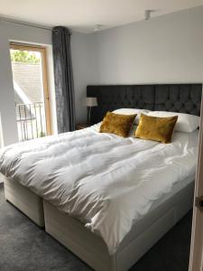 a bedroom with a large white bed with gold pillows at Apt 2, Frasers Close in Kirkwall +1 photo