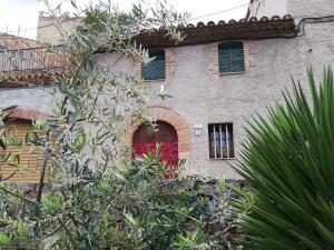 un bâtiment avec une porte rouge et un arbre dans l'établissement Cal Batistet Ferrer, à Torroja