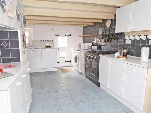 a kitchen with white cabinets and a stove at Woodpecker Cottage in Helston