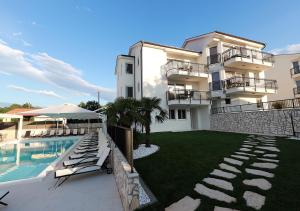 a building with a swimming pool next to a resort at Cool Šilo Appartement Resort in Šilo