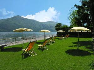 a row of lawn chairs and umbrellas on a beach at Hotel Campagna in Cannobio