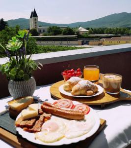stół z dwoma talerzami produktów śniadaniowych i napojów w obiekcie Villa Marinko w Medziugorie