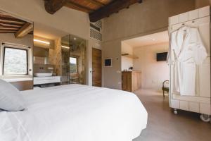 a bedroom with a large white bed and a bathroom at Torre di Baratti Bio Resort in Populonia
