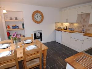 a kitchen with a table and a clock on the wall at Jordan House in Boscastle