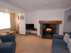 a living room with a fireplace and blue couches at The Keep Pot in Port Isaac