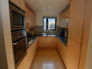 a large kitchen with wooden cabinets and a window at Pine Cottage in Falmouth