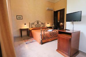 une chambre avec un lit et une télévision à écran plat dans l'établissement Dimora Relais Excelsa, à Gallipoli