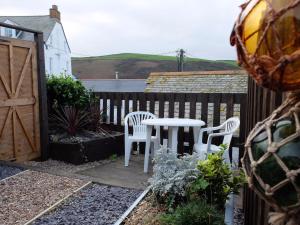 un patio con mesa, sillas y una valla en The Keep Pot en Port Isaac