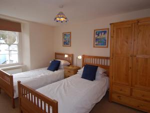 a bedroom with two beds with blue pillows at Jordan House in Boscastle