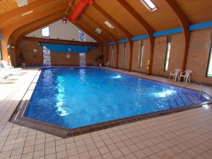 a large swimming pool with blue water in a building at Pine Cottage in Falmouth