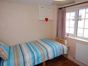 um pequeno quarto com uma cama e uma janela em The Barn em Camelford