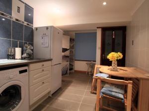 a kitchen with a washer and a table and a refrigerator at The Keep Pot in Port Isaac