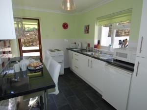 a kitchen with white cabinets and a black counter top at Trevillas in St Austell