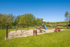 a playground with a swing set and a bench at Apartamenty Sun & Snow Osiedle Wybrzeże in Ustronie Morskie