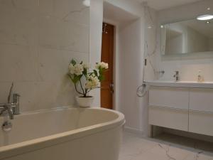 un baño blanco con bañera, lavabo y un jarrón de flores en Lakeside, en Millbrook 14 fotos más
