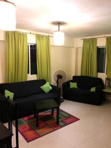 uma sala de estar com dois sofás pretos e cortinas verdes em Apartamento Aquarel em Boca Chica